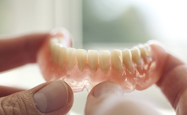 Person holding clear dental aligner or retainer against light background.